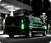 Black luxury van at a hotel entrance at night